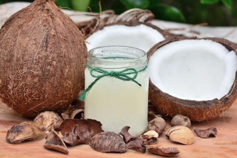 Coconut oil in a glass jar with whole and split coconuts, used for healthy hair care